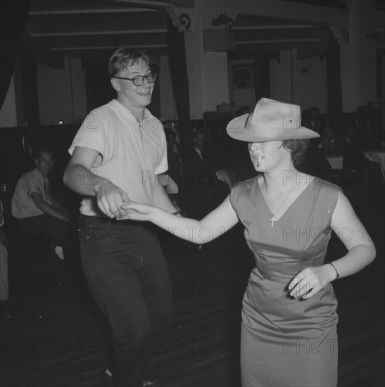 Couple at a Jazz Ball. A young couple dance together at a Jazz Ball. The woman wears a trilby hat, a cigarette hanging from the corner of her mouth. Kenya, 21 September 1957. Kenya, Eastern Africa, Africa.