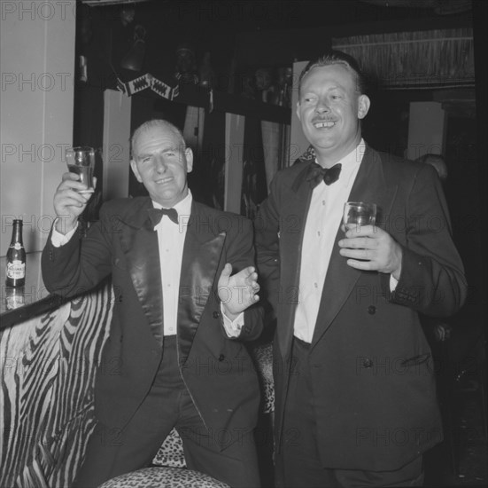 At the Equator Club, Kenya. Two European men dressed in suits raise their glasses for the camera propped against the zebra-striped bar of the Equator Club. Nairobi, Kenya, 21 September 1957. Nairobi, Nairobi Area, Kenya, Eastern Africa, Africa.