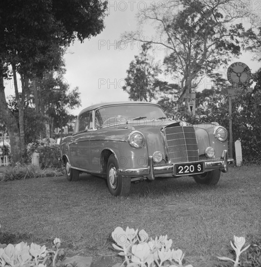 A shiny new Mercedes. A shiny new Mercedes car is displayed on a lawn bordered by flowers at the D.T. Dobie stand at the Royal Show. Kenya, 25 September 1957. Kenya, Eastern Africa, Africa.