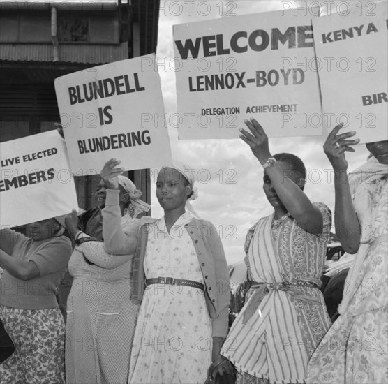 Female Kenyan demonstrators. Several Kenyan women involved in a peaceful demonstration at an airport, hold up placards on the arrival of politican Alan Tindal Lennox-Boyd. Amongst these are two that read: 'Blundell is Blundering' and 'Welcome Lennox-Boyd, Delegation Achievement'. Kenya, 11 October 1957. Kenya, Eastern Africa, Africa.