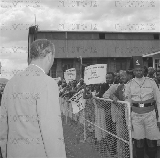 Lennox-Boyd faces demonstrators. Alan Tindal Lennox-Boyd (1904-1983) approaches a peaceful crowd of Kenyan demonstrators, held back by askaris (soldiers) behind a barrier. Amongst the placards on display are two that read: 'Kenya Highlands, Our Birthright' and 'Blundell is Blundering'. Kenya, 11 October 1957. Kenya, Eastern Africa, Africa.