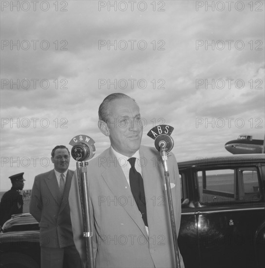 Lennox-Boyd's broadcast. Alan Tindal Lennox-Boyd (1904-1983) broadcasts a speech over microphones marked 'C & W' and 'ABS' on his arrival to a Kenyan airstrip. Kenya, 11 October 1957. Kenya, Eastern Africa, Africa.