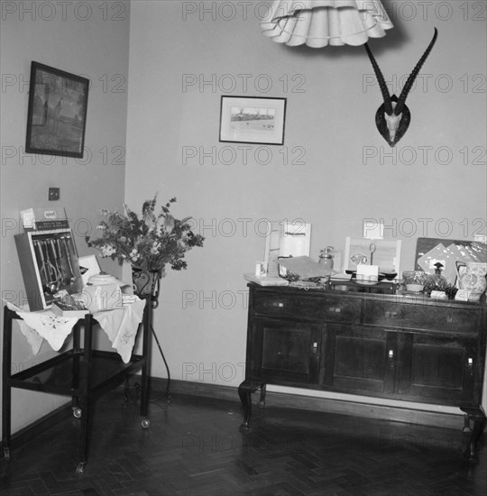 Wedding gifts. Interior shot of a room containing wedding gifts received by the newlywed Hodgson-Wilkinson couple. Kenya, 12 October 1957. Kenya, Eastern Africa, Africa.