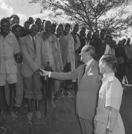 Lennox-Boyd visits Fort Hall. Publicity shot of Alan Tindal Lennox-Boyd (1904-1983) shaking the hand of an elderly Kenyan man during his visit to the Fort Hall district. Kangema, Kenya, 15 October 1957. Kangema, Central (Kenya), Kenya, Eastern Africa, Africa.