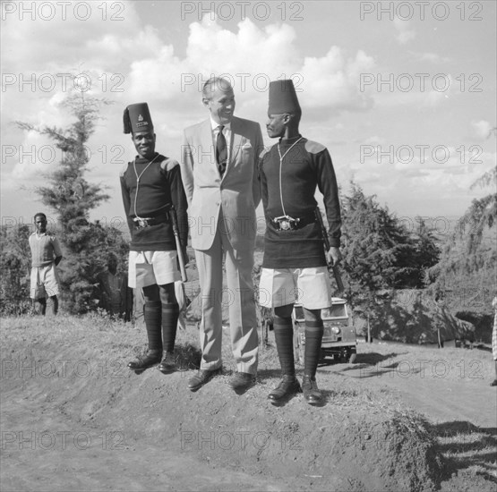 Lennox-Boyd jokes with askaris. Alan Tindal Lennox-Boyd (1904-1983) jokes with two uniformed askaris (soldiers) on his visit to the Fort Hall district. Kangema, Kenya, 15 Oct 1957. Kangema, Central (Kenya), Kenya, Eastern Africa, Africa.