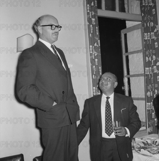 Prudential Insurance cocktail party. A suited businessman stands on a chair to deliver a speech at a Prudential Insurance cocktail party. Kenya, 16 October 1957. Kenya, Eastern Africa, Africa.