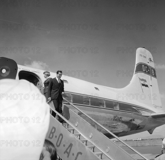 Arrival of Aga Khan IV. Aga Khan IV, Prince Karim Al Husseni, disembarks from a plane at a Kenyan airport. When this photograph was taken, he had only recently inherited the title from his grandfather. Probably Nairobi, Kenya, 17 October 1957. Kenya, Eastern Africa, Africa.