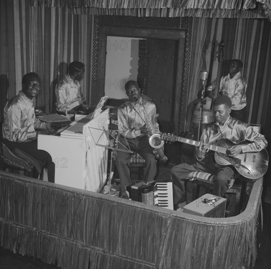 A band at the Equator Club. A five-piece African band perform on a small, confined stage at the Equator Club. The instruments they play include a piano, saxophone, drums, double bass and a guitar. Nairobi, Kenya, 19 October 1957. Nairobi, Nairobi Area, Kenya, Eastern Africa, Africa.