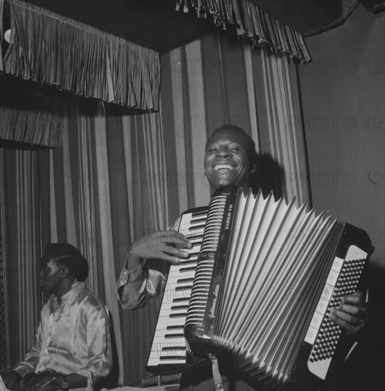 Accordion player. An African musician smiles broadly as he squeezes an accordion during a performance at the Equator Club. Nairobi, Kenya, 19 October 1957. Limuru, Central (Kenya), Kenya, Eastern Africa, Africa.