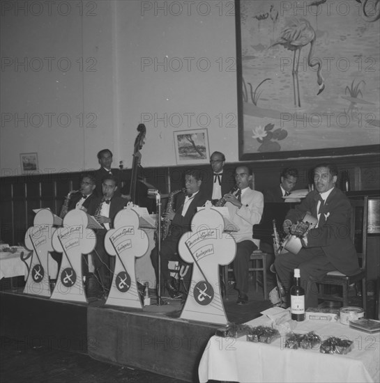 Band at the Northern Counties dance. An eight-piece band performs at the Northern Counties dance, playing a variety of instruments including a guitar, piano, cello and saxophones. Kenya, 2 November 1957. Kenya, Eastern Africa, Africa.