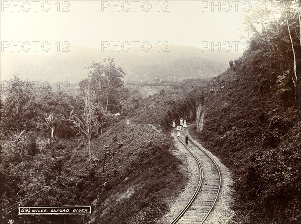 Railway track at Oxford River. A group of children play on the lines of a railway track cut into the side of a mountain at Oxford River. Jamaica, circa 1895. Jamaica, Caribbean, North America .