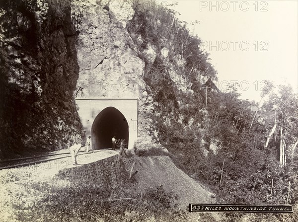 Mountainside tunnel, Jamaica. Three men stand at the entrance to a railway tunnel cut into the side of a mountain. Jamaica, circa 1895. Jamaica, Caribbean, North America .