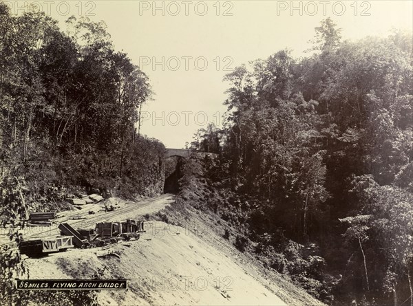 Flying Arch Bridge'. A newly completed stretch of mountainside railway track runs beneath a high arch identified as 'Flying Arch Bridge'. Jamaica, circa 1895. Jamaica, Caribbean, North America .