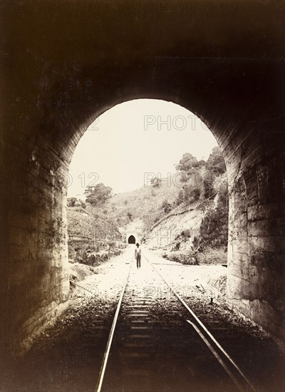 Railway tunnel, Jamaica. View from inside a railway tunnel looking out towards a man who stands on the tracks. A second tunnel is visible in the distance. Jamaica, circa 1895. Jamaica, Caribbean, North America .