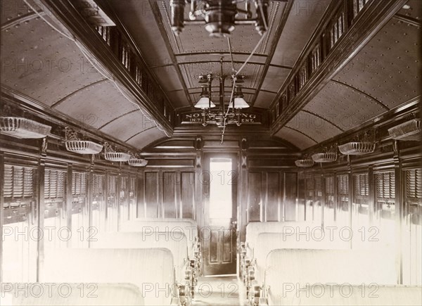 First class carriage, Jamaica. Interior of a Jamaica Railway first class carriage featuring padded seats, overhead baggage storage, lighting and window blinds. A sign above the door reads: 'No smoking in the compartment'. Jamaica, circa 1895. Jamaica, Caribbean, North America .
