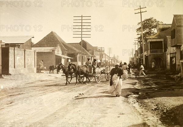 Kingston tram lines. Rails laid down for mule-drawn trams criss-cross a busy road crowded with pedestrians and horse-drawn carts. Kingston, Jamaica, circa 1895. Kingston, Kingston, Jamaica, Caribbean, North America .