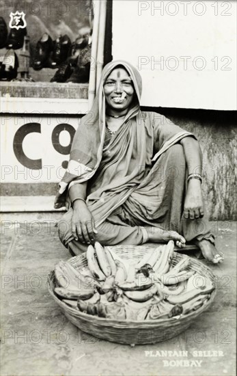 Plantain seller, Bombay. A smiling woman sells plantains from a basket on a city street. Bombay (Mumbai), India, circa 1940. Mumbai, Maharashtra, India, Southern Asia, Asia.