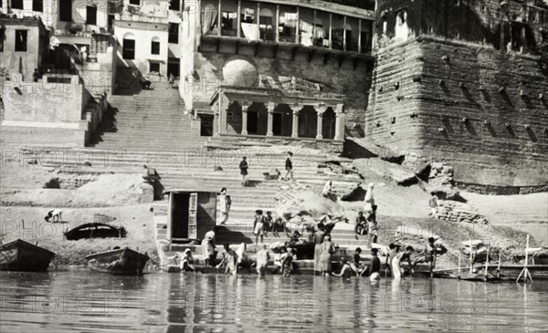 A bathing ghat at Benares. Religious pilgrims bathe at a ghat (stepped wharf) on the River Ganges at Benares, one of Hinduism's holiest sites. The famous Hindu temples of Scindia Ghat and Manikarnika Ghat are located nearby. Benares, United Provinces (Varanasi, Uttar Pradesh), India, circa 1925. Varanasi, Uttar Pradesh, India, Southern Asia, Asia.
