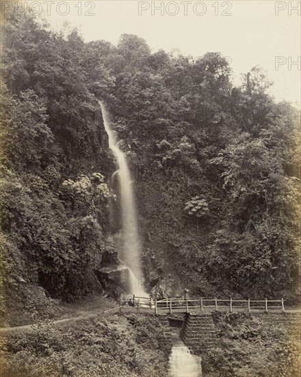 Victoria Falls, Darjeeling. A narrow cascade of water at Victoria Falls tumbles down a heavily wooded hillside and underneath a small pedestrian bridge. Darjeeling, India, circa 1885. Darjeeling, West Bengal, India, Southern Asia, Asia.
