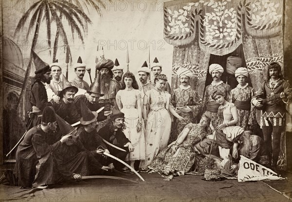 Cast of Lalla Rookh. The European cast in a pantomime of Lalla Rookh. The group stand on stage in front of a painted backcloth, dressed in a variety of Oriental and medieval costumes with accessories including turbans, sorcerer's pointed hats and exaggerated beards. Calcutta (Kolkata), India, circa 1885. Kolkata, West Bengal, India, Southern Asia, Asia.