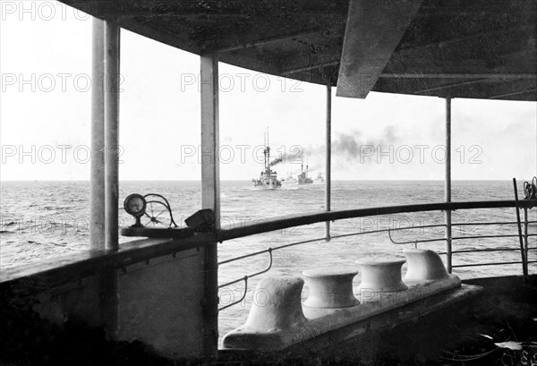 Battleships in escort. View from the deck of HMS Medina, the royal yacht transporting King George V and Queen Mary to India for the Coronation Durbar at Delhi. The battleships in the distance are escorts to the royal voyage. Location unknown, November 1911.