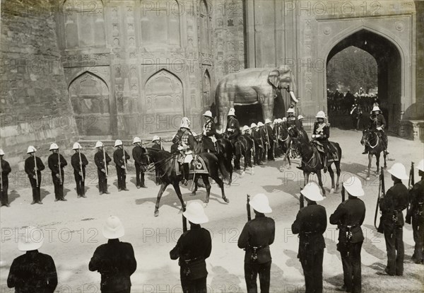 King George V's state entry. The state entry of King George V (r.1910-36) into Delhi, passing through the arched gateway of the Delhi Fort. The route is lined with uniformed military officers, armed and standing to attention. Delhi, India, 7 December 1911. Delhi, Delhi, India, Southern Asia, Asia.