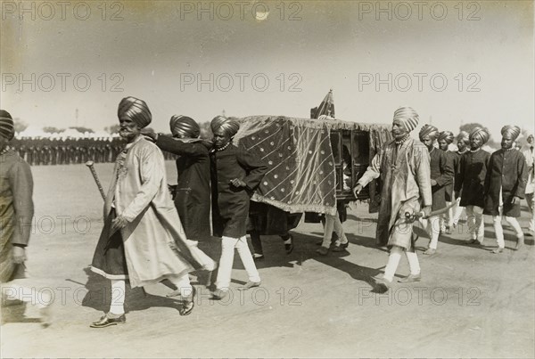 Maharajah in a sedan chair. A procession of attendants dressed in ceremonial attire, carry a sedan chair containing an unidentified Maharajah. This was one of many Indian princes who travelled to Delhi to pay homage to King George V, Emperor of India. Delhi, India, circa 9 December 1911. Delhi, Delhi, India, Southern Asia, Asia.