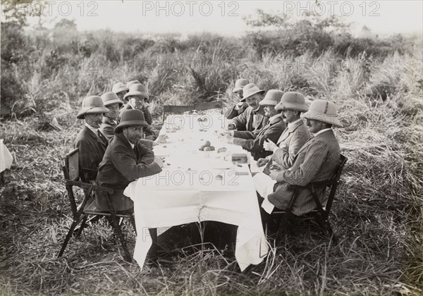 Royal lunch in the jungle. King George V (r.1910-36), seated front left, takes lunch with his hunting companions in the jungle. The King travelled to Nepal to hunt in Chitwan Valley following his Coronation Durbar in Delhi. Narayani, Nepal, 18 December 1911., Narayani, Nepal, Southern Asia, Asia.