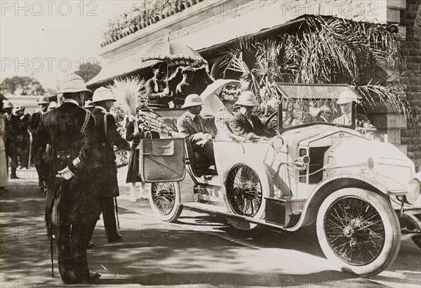 Driving to Nagpur Fort. A uniformed official closes the door of a convertible car containing King George V (r.1910-36) and Queen Mary. The royal couple are pictured outside Nagpur railway station on their way to visit the city's fort. Nagpur, India, circa 4 January 1912. Nagpur, Maharashtra, India, Southern Asia, Asia.