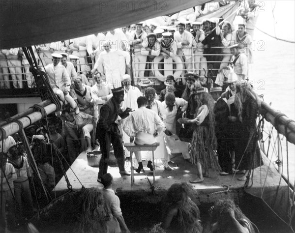 Antics aboard the S.S. Balmoral Castle. Crew members aboard the S.S. Balmoral Castle clown about on deck wearing costumes and wigs, possibly for a traditional 'crossing the line' naval initiation ceremony. The ship was transporting the Duke and Duchess of Connaught to South Africa, where they were due to open the new Union Parliament in Cape Town. Probably Atlantic Ocean, Africa, October 1910. Africa.