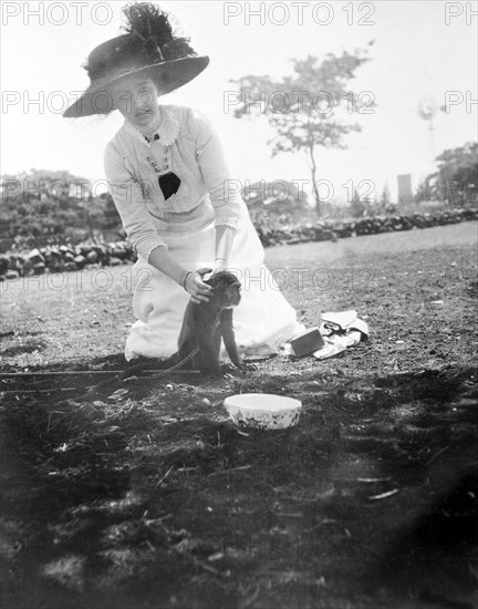 Princess Patricia with a chained monkey. Princess Patricia, the Duke of Connaught's daughter, kneels on the ground to stroke a chained monkey during a royal visit to Livingstone. This was one of several stops made by her parents following their official visit to Cape Town to open the new Union Parliament. Livingstone, Northern Rhodesia (Zambia), 12-15 November 1910. Livingstone, South (Zambia), Zambia, Southern Africa, Africa.