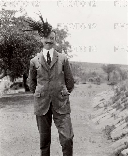 Wearing a foliage hat. A member of the Duke of Connaught's royal entourage strikes a comical pose, wearing what appears to be a hat constructed from leaves. Near Livingstone, Northern Rhodesia (Zambia), 12-15 November 1910. Livingstone, South (Zambia), Zambia, Southern Africa, Africa.