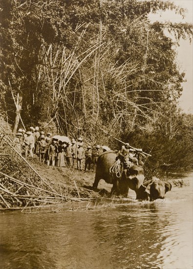 Gentle persuasion'. The Maharajah of Mysore (Krishna Raja Wadiyar IV, 1884-1940) and his guests, Lord and Lady Minto, watch from a river bank in the Kakankota Forests as a 'koomkee' (tame elephant) persuades a newly captured wild elephant to drink. Karnataka, India, 1909., Karnataka, India, Southern Asia, Asia.