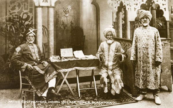 Soothsayers at Blackpool Tower. A good example of Orientalism, this image shows three Indian men dressed in fine clothes, ready to provide a 'traditional' soothsaying (fortune telling) service to tourists visiting Blackpool Tower. Indian paraphernalia surrounds the stall, intended to enhance the credibility of its practitioners. Blackpool, England, circa 1910. Blackpool, Lancashire, England (United Kingdom), Western Europe, Europe .