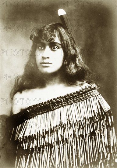 Young Maori woman. Studio portrait of a young Maori woman whose traditional dress has been made using the taniko weaving process. Her hair is decorated with a single feather. New Zealand, circa 1903. New Zealand, New Zealand, Oceania.