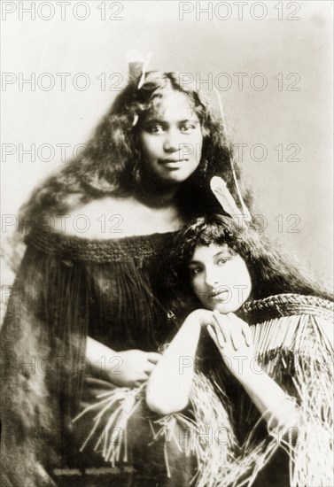 Two Maori women. Studio portrait of two young Maori women whose traditional dress has been made using the taniko weaving process. Both wear decorative feathers in their hair. New Zealand, circa 1903. New Zealand, New Zealand, Oceania.