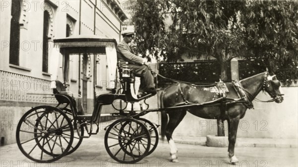 Hackney carriage, Gibraltar. A horse-drawn hackney carriage waits outside a building in a city street. Gibraltar, circa 1920. Gibraltar, Gibraltar, Gibraltar, Mediterranean, Europe .