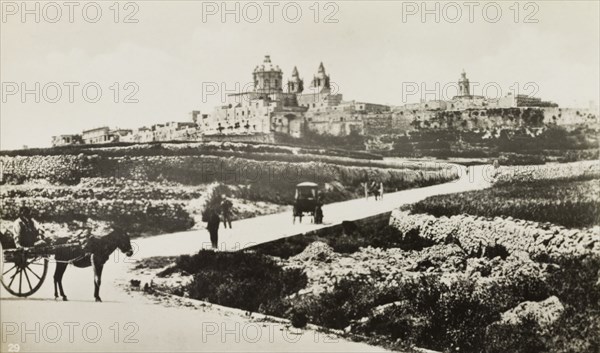 Outskirts of Mdina. People travel along a road on the outskirts of Mdina, the 'citta vechia' or old city. Mdina, Malta, circa 1900. Mdina, Malta, Malta, Central Europe, Europe .