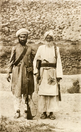 Armed Afridi men. Portrait of two Afridi men at the north west frontier, both armed with rifles and belts of bullets. An original caption comments: 'An example of tribesmen, with their modern rifles, most probably stolen'. North West Frontier Province, India (Pakistan), circa 1915., North West Frontier Province, Pakistan, Southern Asia, Asia.