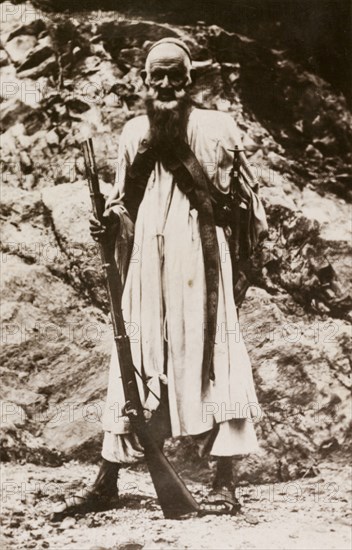 An elderly sniper. Portrait of an elderly man, possibly an Afridi, armed with a rifle and sword. North West Frontier Province, India (Pakistan), circa 1915., North West Frontier Province, Pakistan, Southern Asia, Asia.