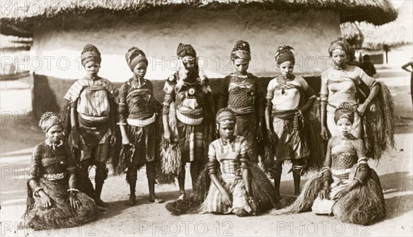 Sierra Leone dancers. Nine young women dressed in traditional dance costume pose for the camera wearing grass skirts, headscarves and face paint. Sierra Leone, circa 1910. Sierra Leone, Western Africa, Africa.