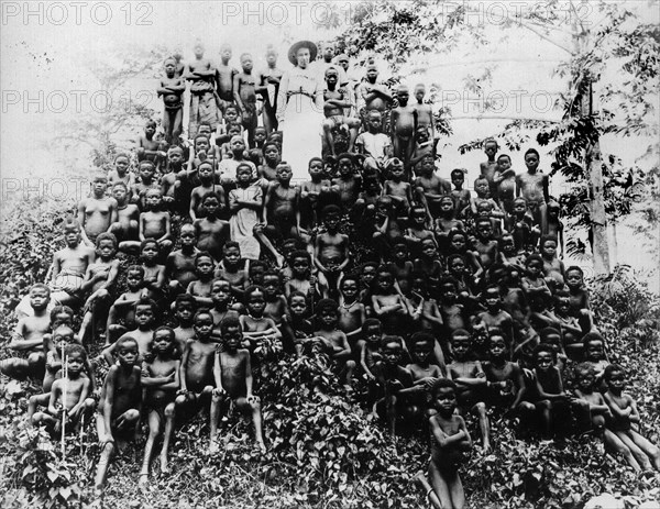 A pyramid of Congolese children. Missionary Alice Seeley Harris, dressed completely in white, stands above a pyramid of Congolese children. Congo Free State (Democratic Republic of Congo), circa 1905. Congo, Democratic Republic of, Central Africa, Africa.