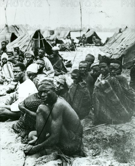 Ethiopian slave market. Male slaves sit on the ground in groups outside makeshift tents at an Ethiopian slave market. Ethiopia, circa 1930. Ethiopia, Eastern Africa, Africa.