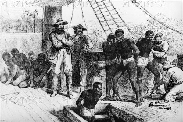 Boarding a slave ship. African slaves are mannacled and shackled by European slave traders as they board an Atlantic slave ship bound for the Caribbean. Africa, circa 1820. Africa.