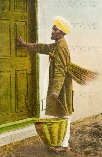 An Indian 'mehtar'. An illustration depicting a turbaned 'mehtar' (sweeper) visiting a house. He carries a brush under one arm and a large basket in his hand. India, circa 1910. India, Southern Asia, Asia.