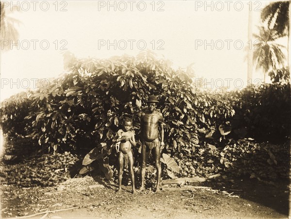 Inhabitants of Bioko. Portrait of a semi-naked man and boy, inhabitants of the island of Bioko. The boy carries a small dog under his arm, the man sports a bowler hat. Bioko, Equatorial Guinea, circa 1930., Bioko Norte, Equatorial Guinea, Central Africa, Africa.