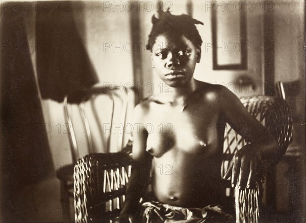 Young woman from Bioko. Portrait of a semi-naked young woman from Bioko, posed seated in a wickerwork chair. Bioko, Equatorial Guinea, circa 1930., Bioko Norte, Equatorial Guinea, Central Africa, Africa.