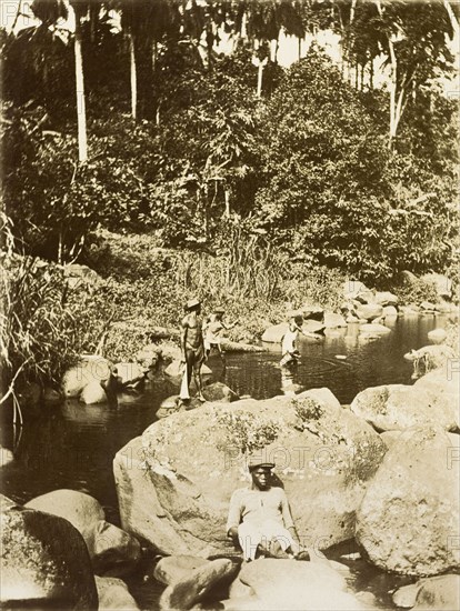 Relaxing by the river. Four men from Bioko relax by a jungle river. Bioko, Equatorial Guinea, circa 1930., Bioko Norte, Equatorial Guinea, Central Africa, Africa.