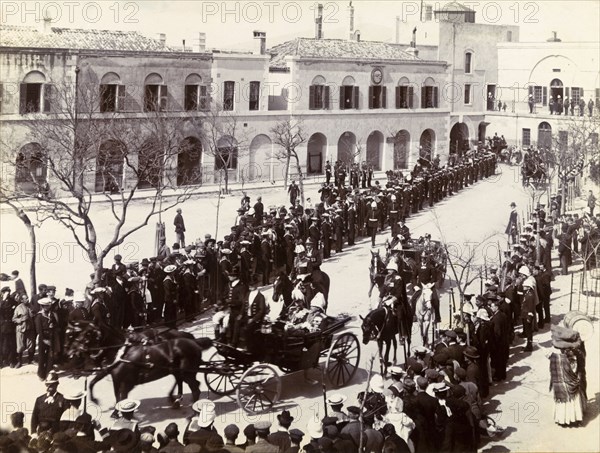 Procession in Gibraltar. Two distinguished gentlemen are driven through crowds gathered in a town square by horse-drawn carriage. This is one of several photographs taken during a royal visit to Gibraltar by King Edward VII (1841-1910) and Kaiser Wilhelm II (1859-1941), and may feature the monarchs themselves. Gibraltar, 1904., Gibraltar, Gibraltar, Mediterranean, Europe .