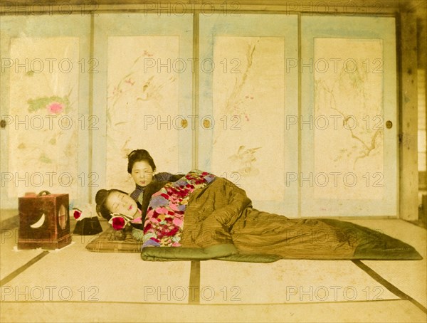 Reclining on a futon. Two Japanese women recline on a traditional futon placed on the floor. Japan, circa 1910. Japan, Eastern Asia, Asia.